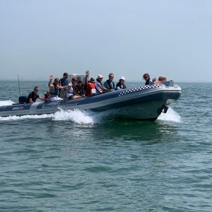 a group of people riding on the back of a boat in the water