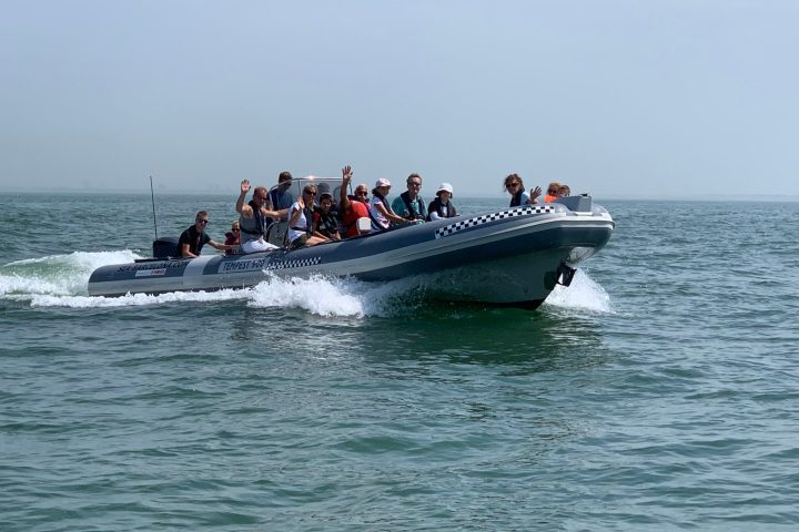 a group of people riding on the back of a boat in the water