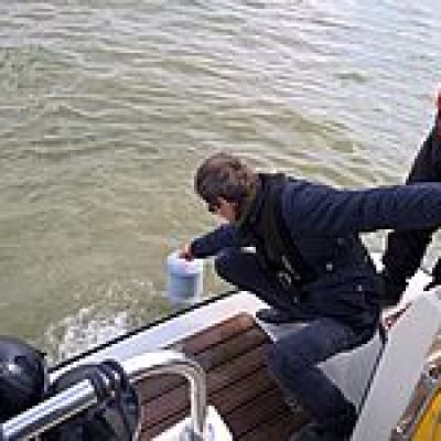 a man riding a motorcycle next to a body of water